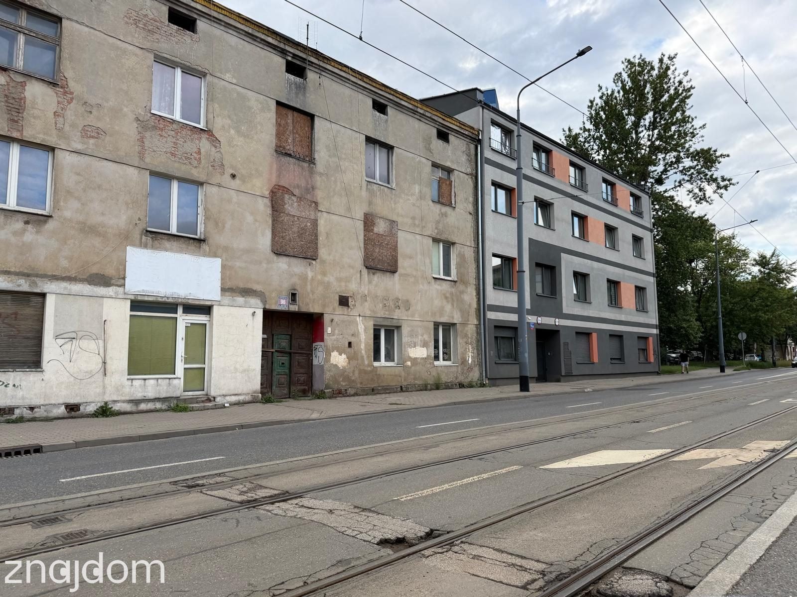 Zdjęcie brunatnej kamienicy sąsiadującej z kolorowym, nowym budynkiem.