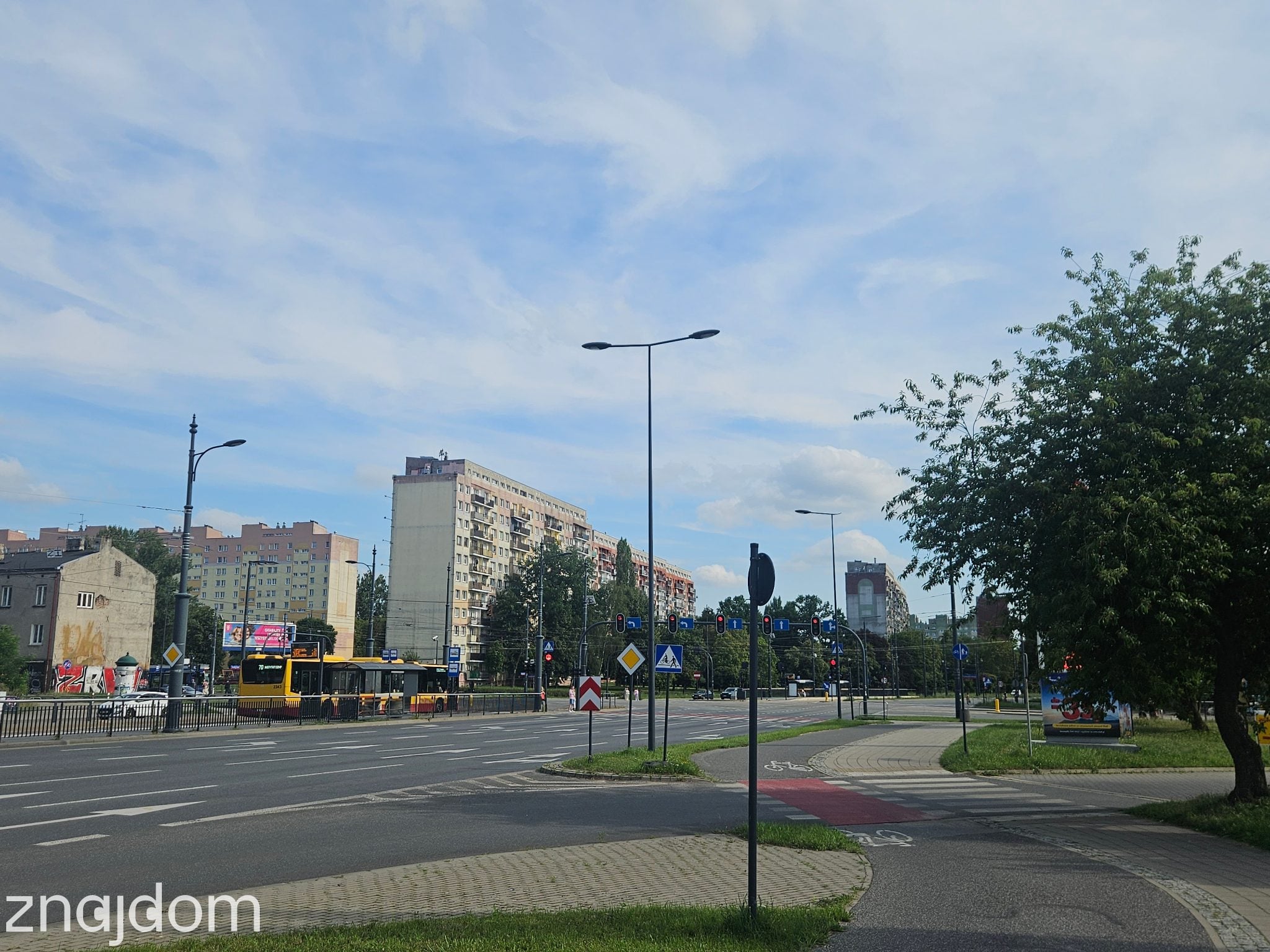 Panorama Zarzewa. Bloki, szerokie ulice, autobus na przystanku, widoczna ścieżka rowerowa.