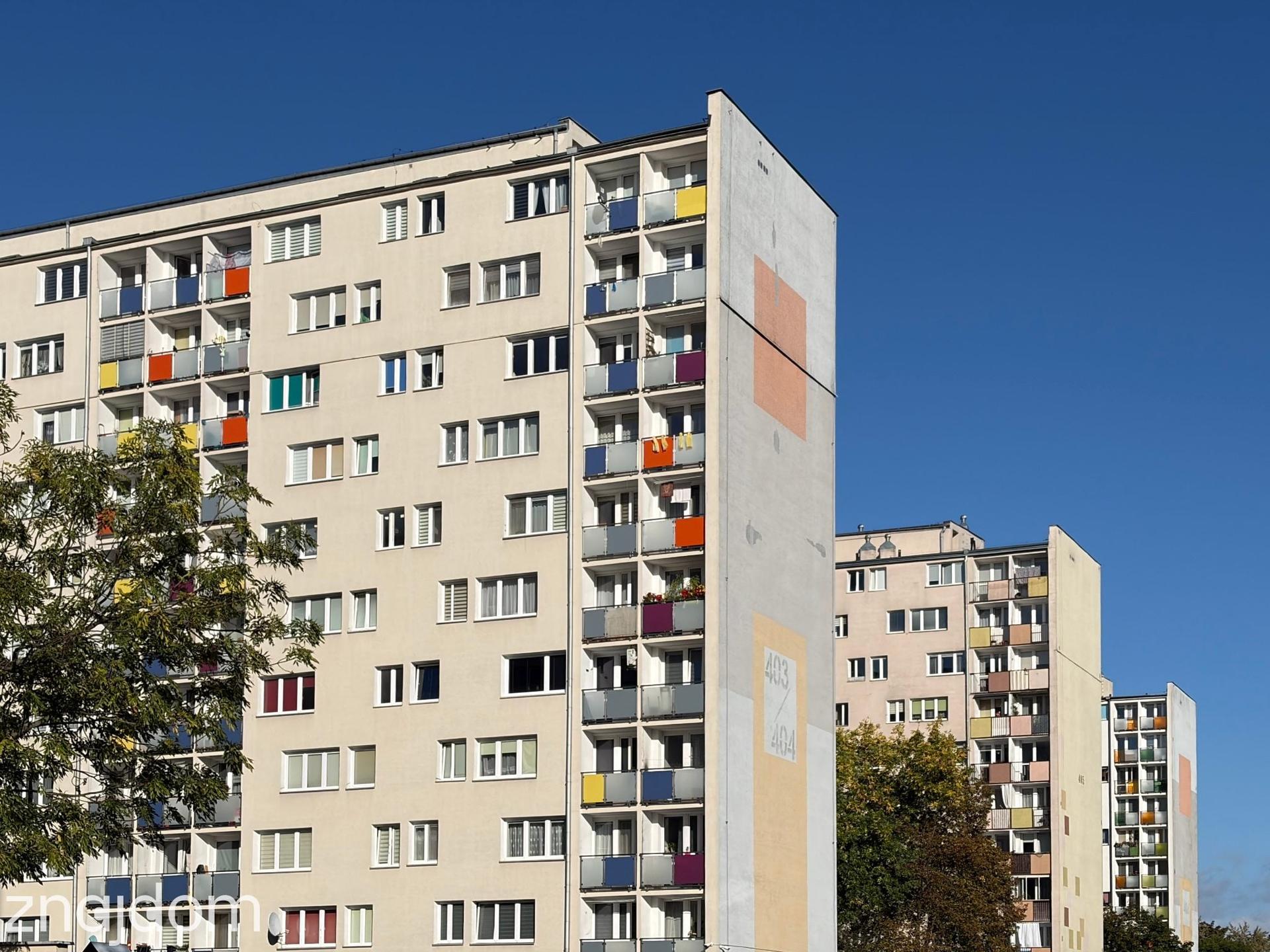 Rząd wysokich bloków z wielkiej płyty z odnowioną elewacją i kolorowymi balkonami na osiedlu Łódź Dąbrowa.