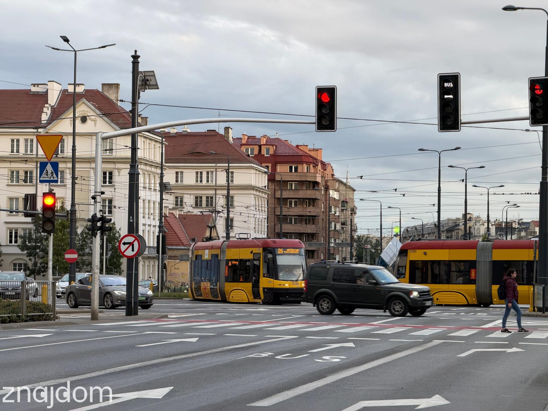 Dwa żółte warszawskie tramwaje mijające się na skrzyżowaniu z wyznaczonym buspasem na Pradze-Północ.