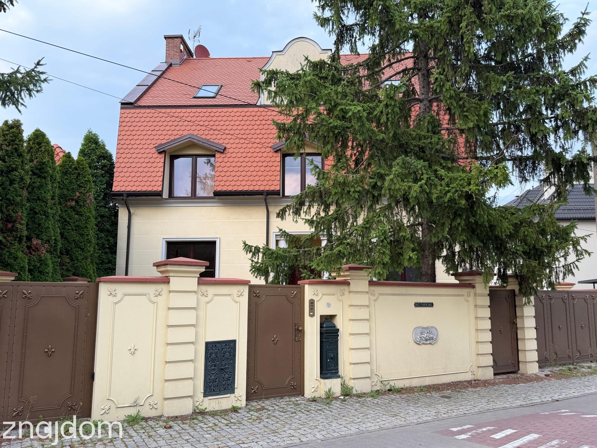 Domek z czerwoną dachówką i ozdobną bramą na Wilanowie.