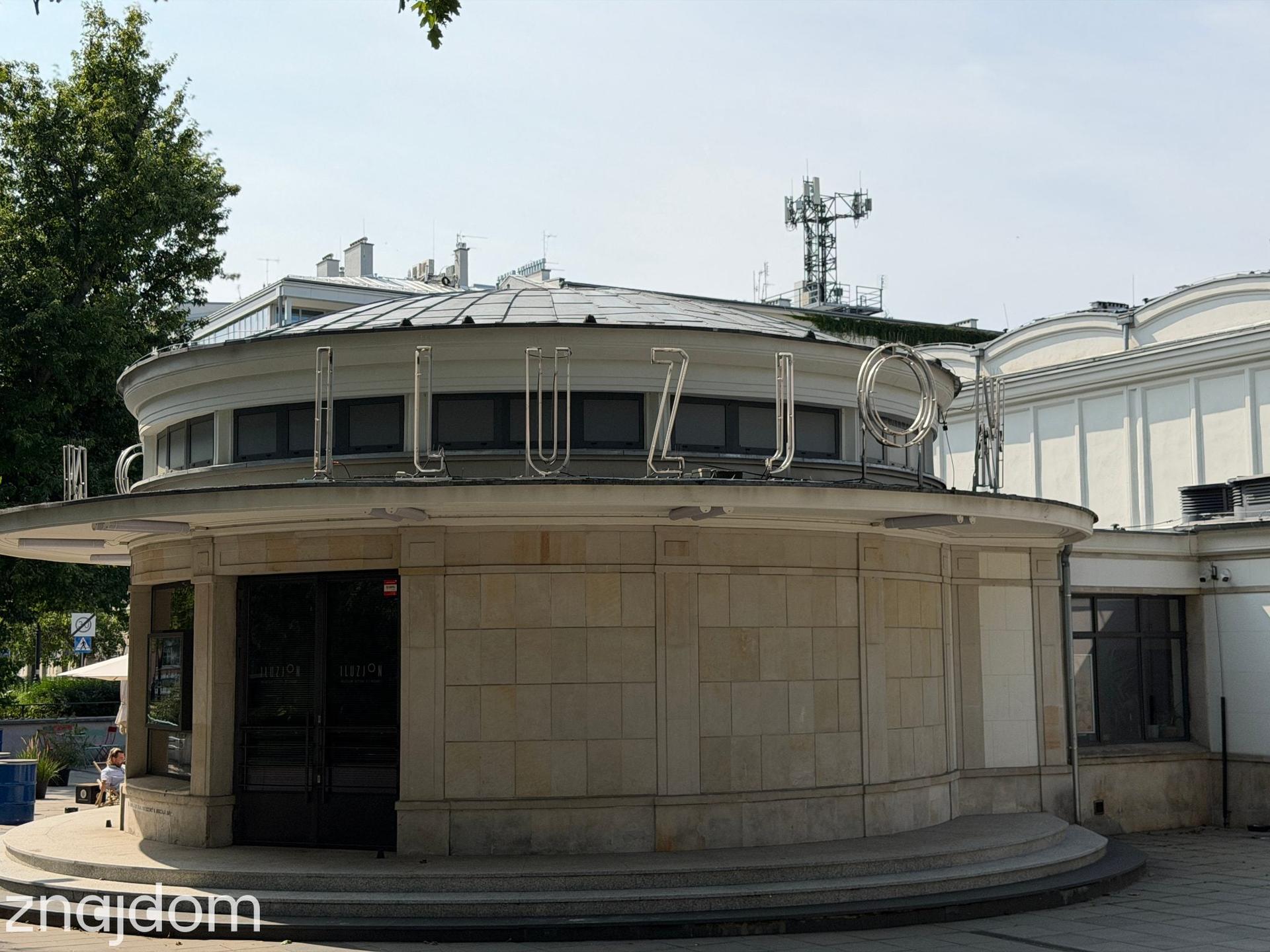 Fasada zabytkowego budynku Kina Iluzjon z charakterystyczną rotundą i neonem na dachu na warszawskim Mokotowie.