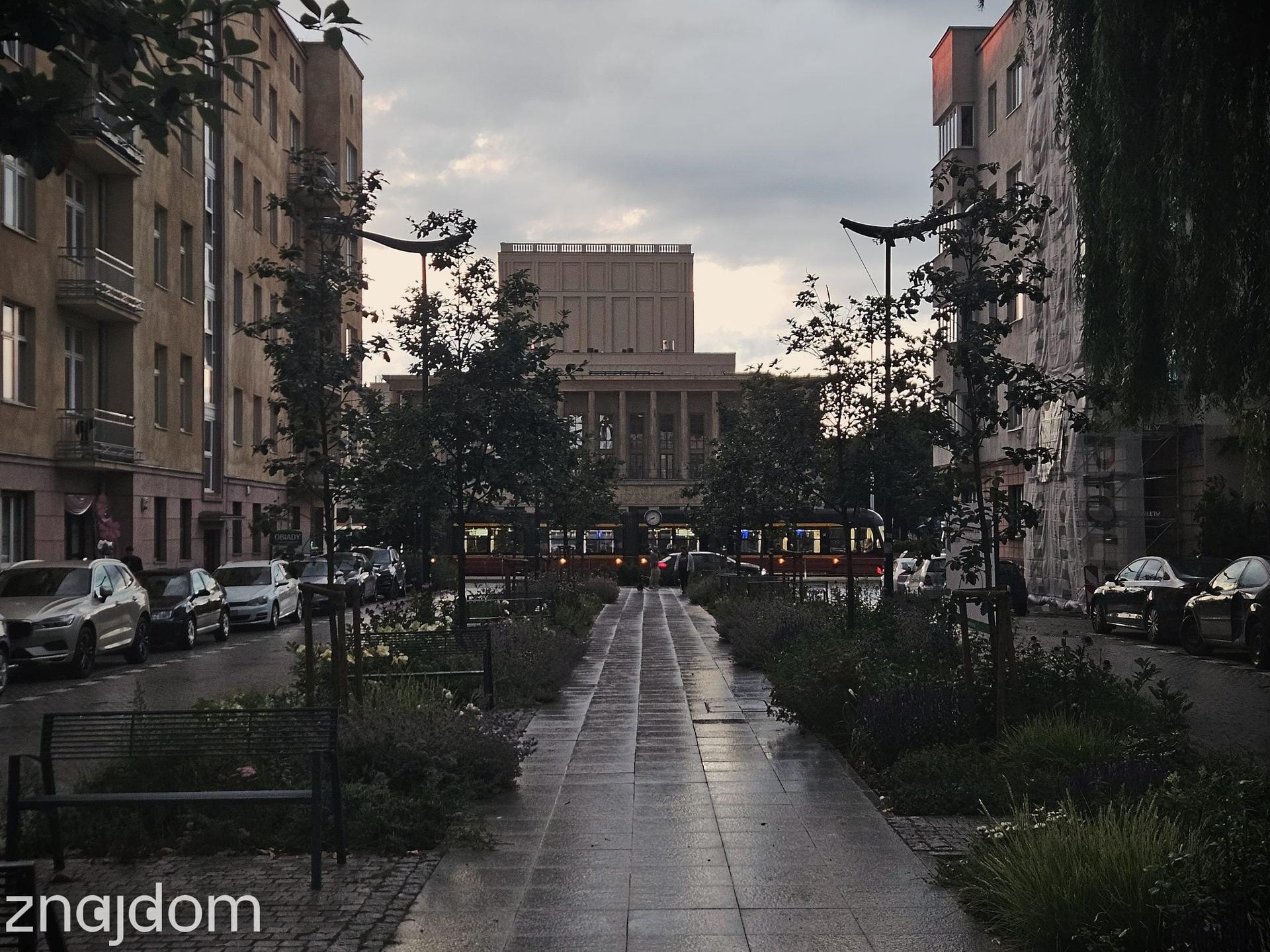 Widok na gmach Teatru wielkiego w Łodzi spomiędzy kamienic odrestaurowanej ulicy Knychalskiego. Przed teatrem czeka tramwaj.