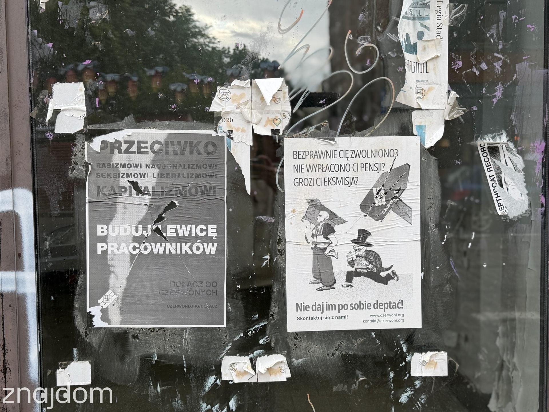 Brudna miejska witryna gęsto zaklejona podartymi plakatami, wlepkami i ulotkami na Pradze-Północ.