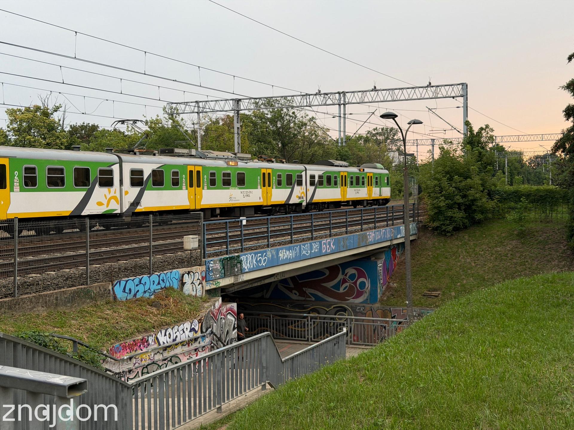 Przejazd kolejowy za stacją Warszawa Ursus, przejeżdża pociąg.