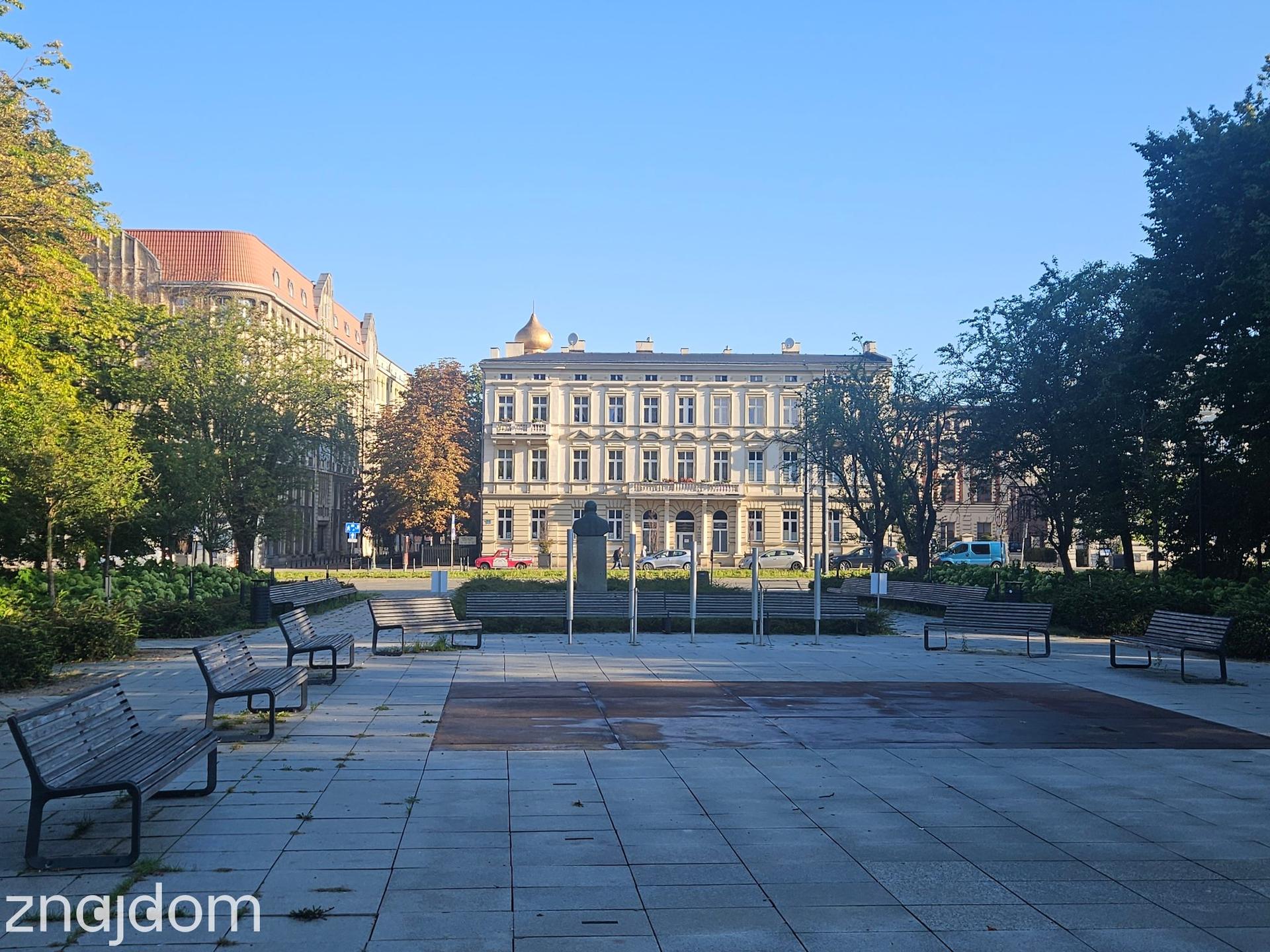 Ławki w Parku Moniuszki w Łodzi. Widok na zabytkową architekturę.
