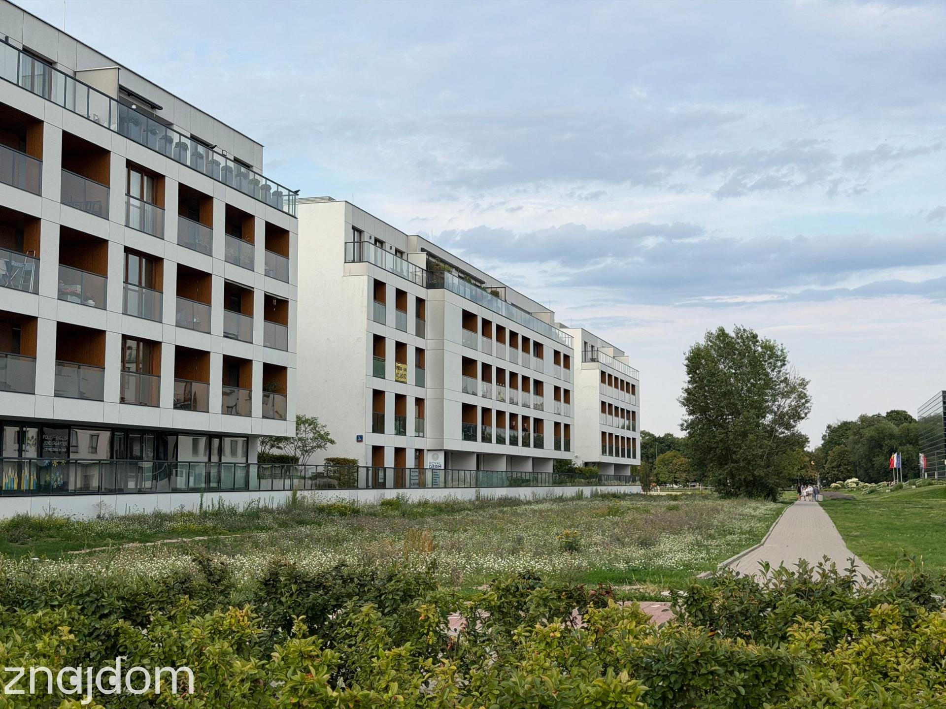Ogrodzone apartamentowce, przed nimi trawnik. Warszawa, Wilanów.