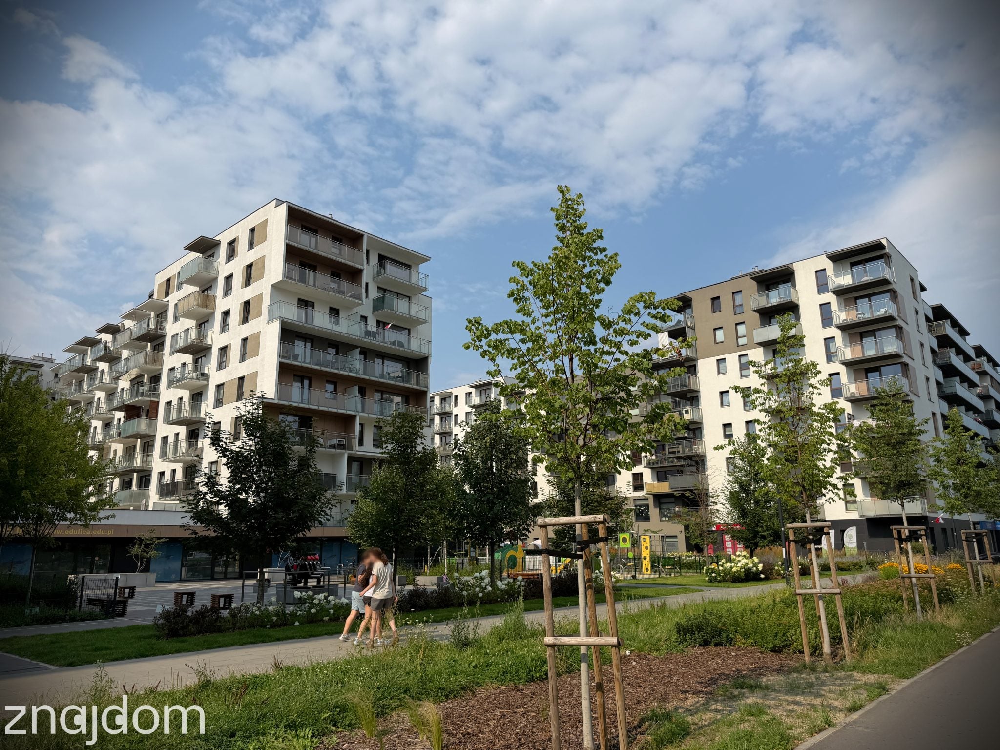 Widok na nowe apartamentwoce otoczone młodymi drzewkami. Warszawa, Wola.